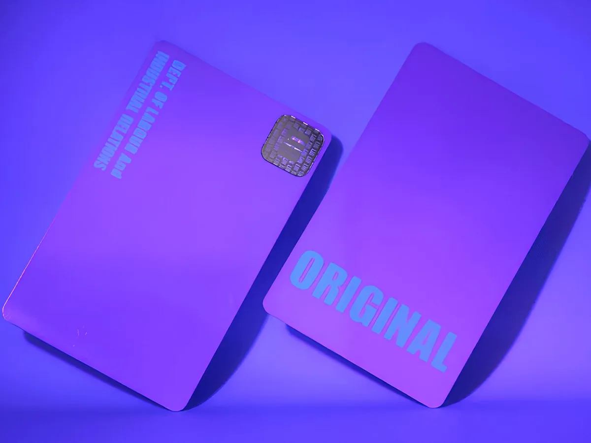 Two cards under ultraviolet light, a layer of print invisible in daylight glowing back in pale blue